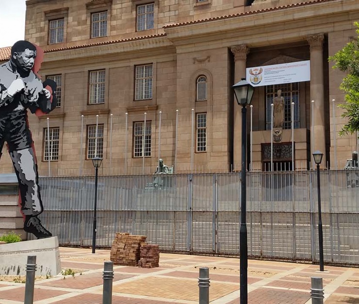 Exterior view of the Johannesburg Magistrate’s Court with a bold sculpture of a boxer in the foreground, symbolising legal battles, financial claims, and the fight for justice.