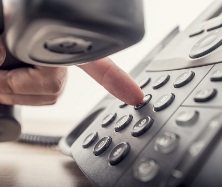 Close-up of a person's hand dialling a number on a landline phone, symbolising the legal and ethical considerations of recording conversations without consent.