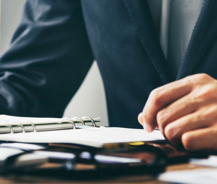 Close-up of a man in a suit sitting at a desk with legal documents and a notebook, symbolising debt set-off analysis or financial legal strategy.