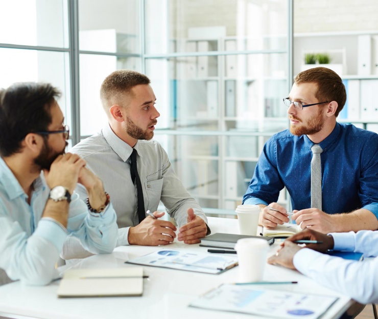Group of professionals in formal attire having a serious discussion in a modern office, representing corporate governance and director liability.