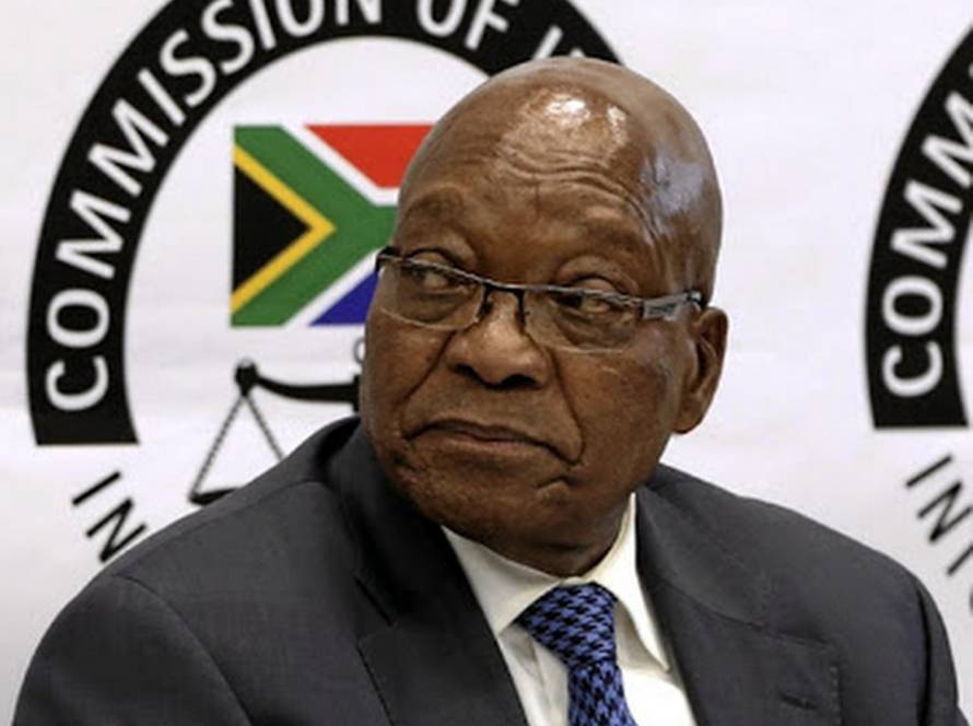 Jacob Zuma seated in front of the State Capture Commission of Inquiry backdrop, symbolising the pursuit of justice regardless of consequence.