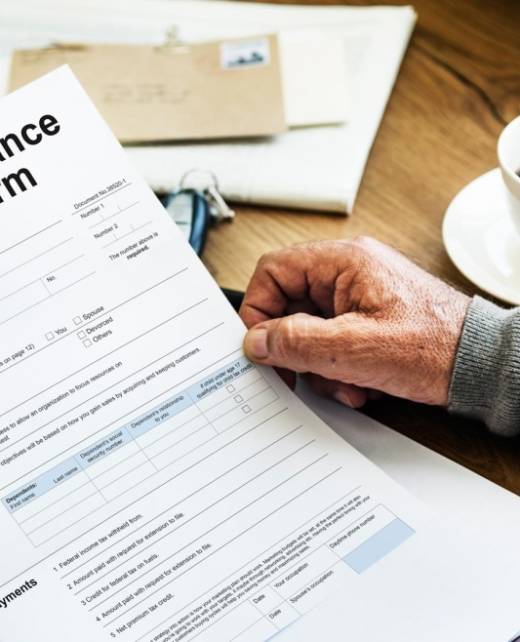Client reviewing a vehicle insurance claim form at a desk with documents and coffee, symbolising insurance dispute resolution and legal support by SWVG Inc.